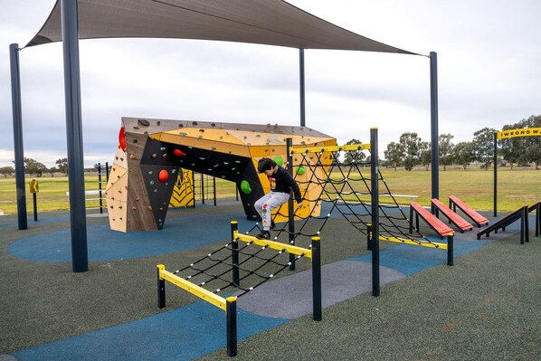 A playground with climbing structures, a net bridge, and a slide. - Serene Tiny House with Amazing Countryside Landscapes in New South Wales (West Wyalong)