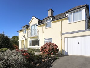 A two-story residential building with a balcony, a garage, and a well-maintained garden. - Hafan (Criccieth)