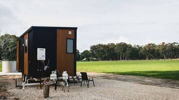 A small cabin with a kitchenette, a table, and chairs outside.
