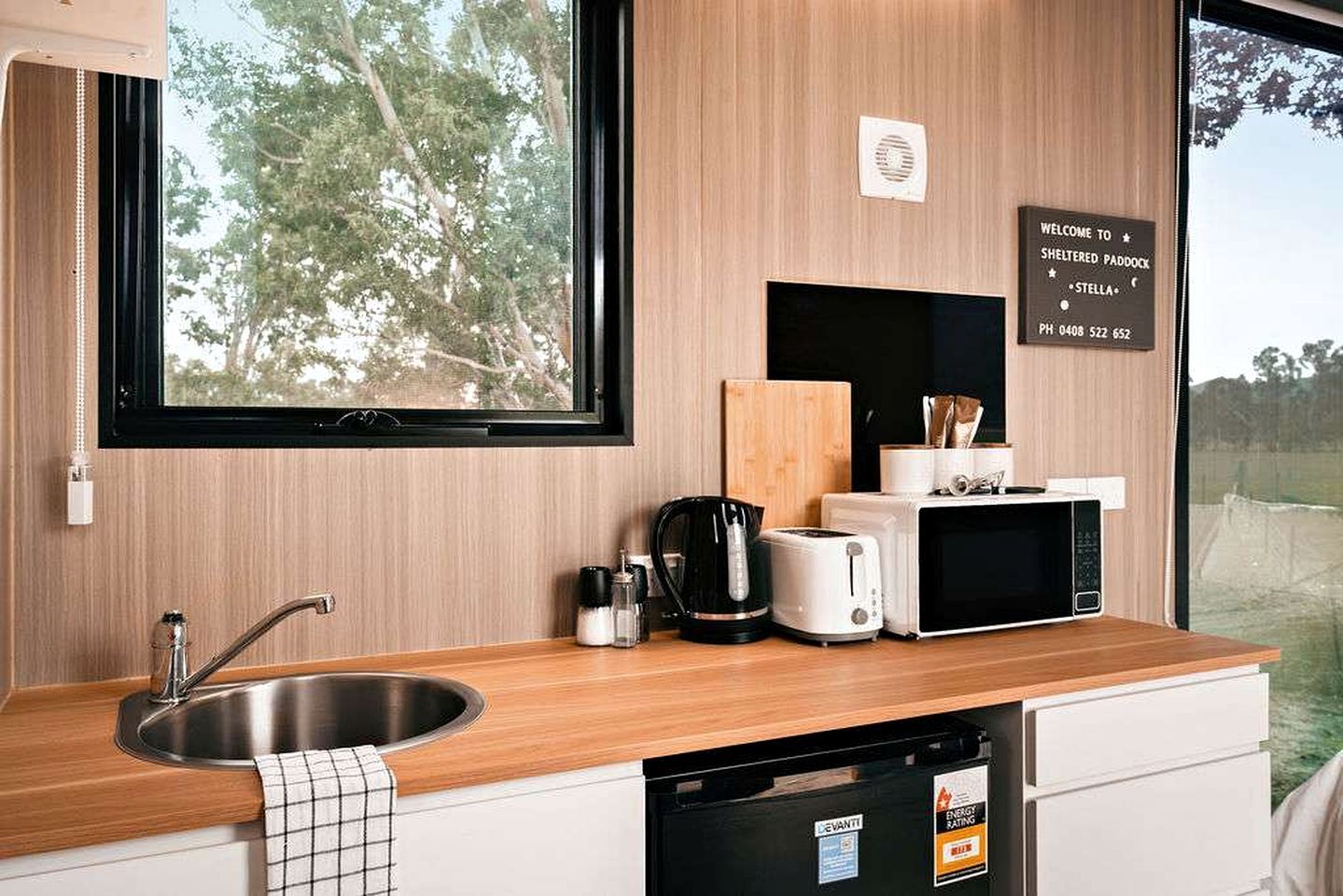 Una cocina moderna con un lavamanos, un tostador, un microondas y una cafetera.