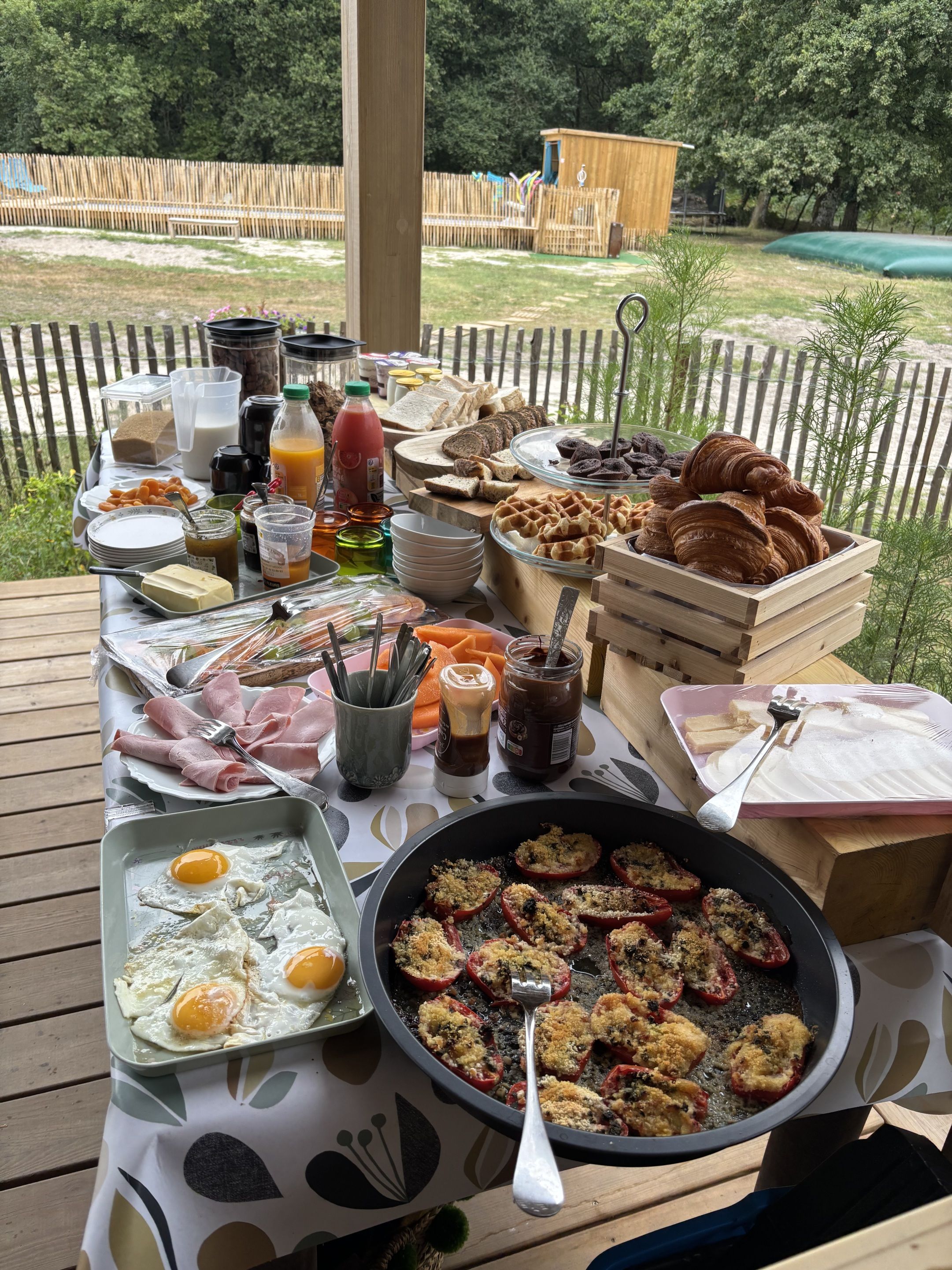 An outdoor breakfast setup with various food items and utensils.