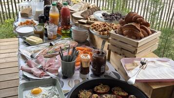 An outdoor breakfast setup with various food items and utensils.