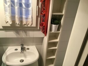 A bathroom with a white sink, a towel rack with a white towel, and a potted plant on a shelf. - Battistero (Florence)