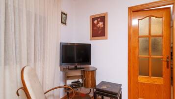 A living room with a television, a wooden door, and a framed picture on the wall.