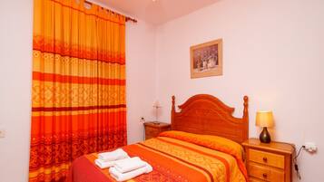 A bedroom with a bed, a nightstand, a lamp, and a painting on the wall.