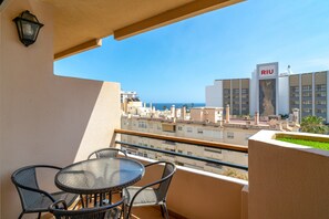 A balcony with a table and chairs, overlooking a cityscape and the sea. - Apartment in Nerja Near Beaches & Pool (Nerja)