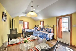 A room with a bed, a dining table set for two, and a window with curtains. - Spacious Cabin for Cozy Group Getaways in Pleasant Mount, Pennsylvania (Pleasant Mount)