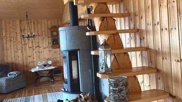 A wooden interior with a fireplace, shelves, and a staircase.