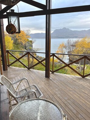 A wooden deck with a view of a lake and mountains.