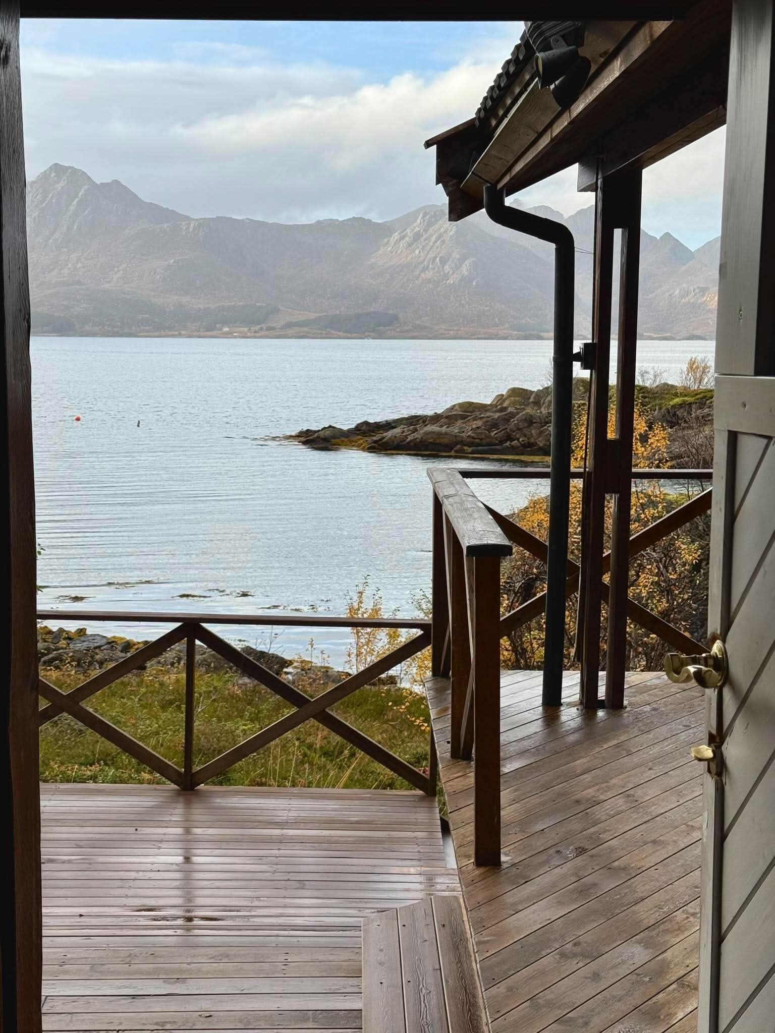 Een houten terras met uitzicht op een meer en bergen.