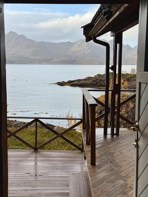 Una terraza de madera con vistas a un lago y montañas.
