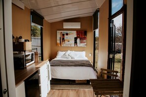 A bedroom with a bed, a desk, a chair, and a window.