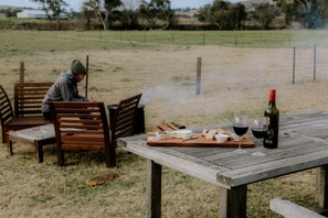 A wooden table with a bottle of wine, glasses, and cheese and bread.