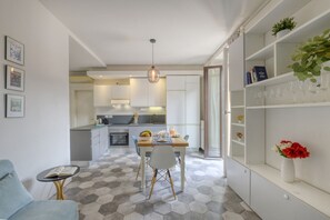 Eine moderne Küche mit Essbereich, einem kleinen Tisch, einem Stuhl und einem Bücherregal mit Dekoration.