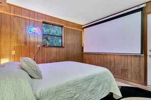 A bedroom with a bed, a neon guitar sign, a window with a mosaic, and a projector screen. - Secluded Glamping Site in Eustis, Florida, with Hot Tub, Fire-Pit and Forest Views (Eustis)