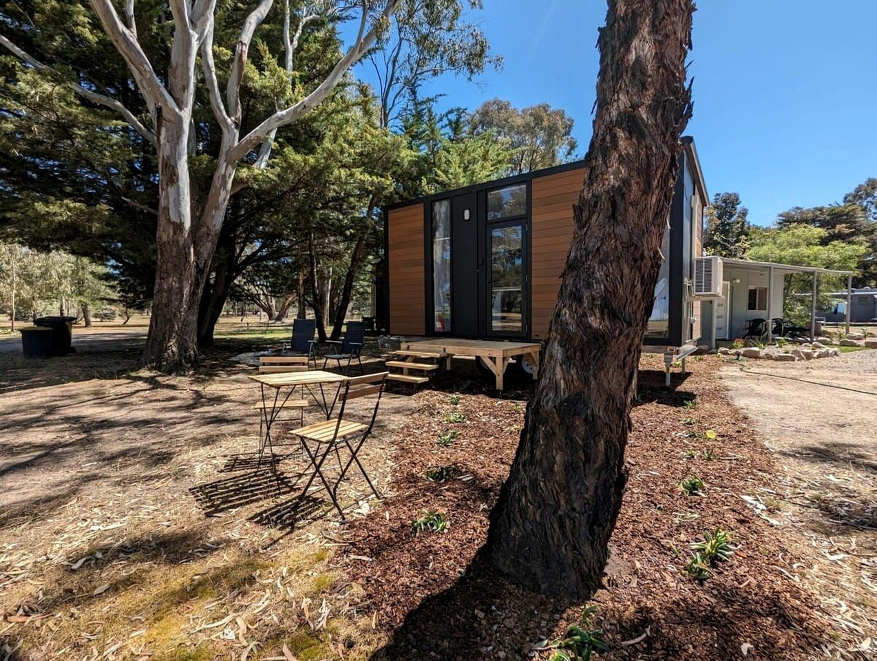 Una casa moderna con terraza, rodeada de árboles y un área de picnic.