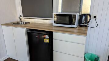 A compact kitchen with a sink, a microwave, a dishwasher, and a trash bin.