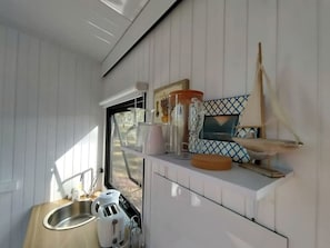 A compact kitchen with a sink, countertop, and various kitchen items.