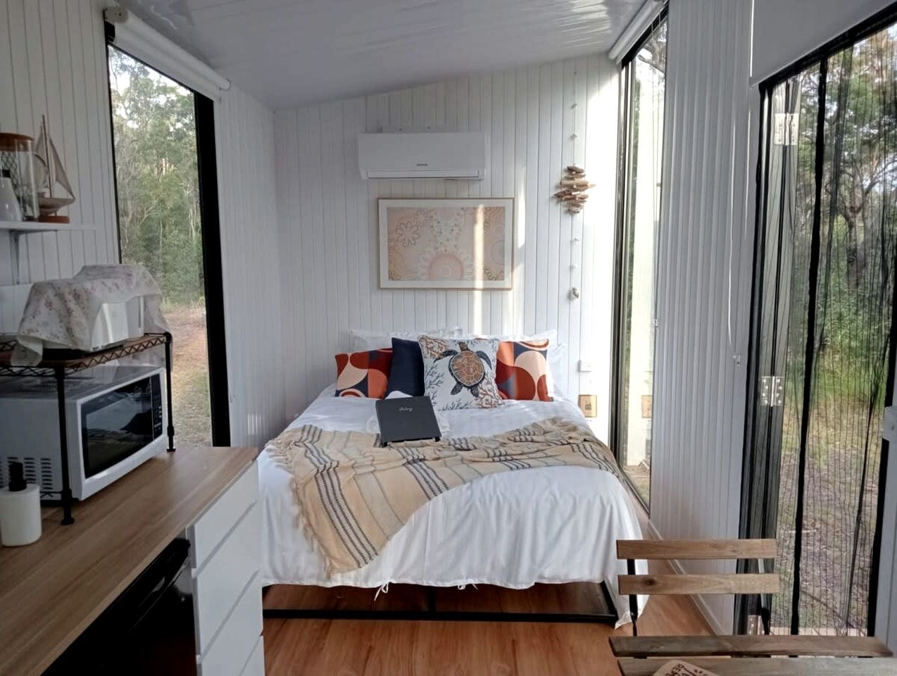 Une chambre avec un lit, un ordinateur portable, un four à micro-ondes et une vue sur l’extérieur.