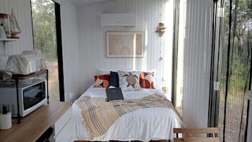 Una camera da letto con un letto, un portatile, un forno a microonde e vista sull'esterno.
