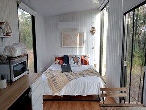 Un dormitorio con cama, laptop, microondas y vistas al exterior.
