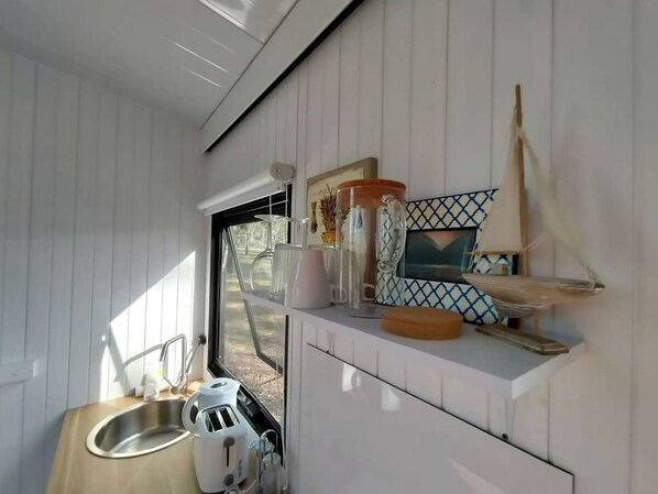 A compact kitchen with a sink, countertop, and various kitchen items.