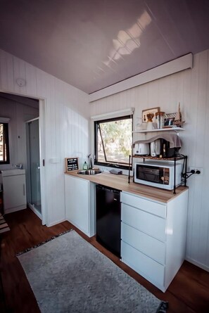 Cocina compacta con ventana, electrodomésticos integrados y un lavamanos pequeño.