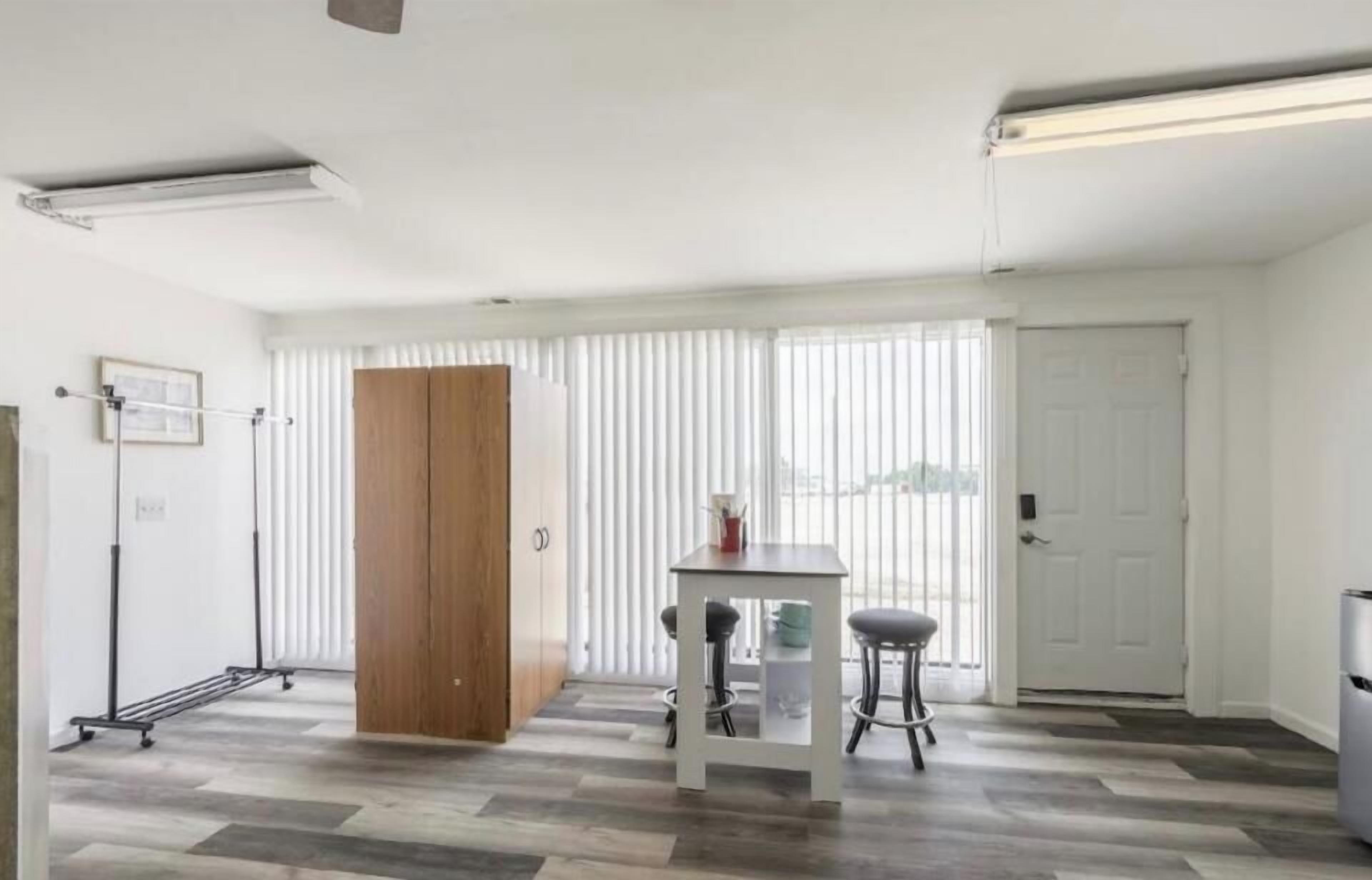 Una habitación con un armario de madera, una mesa con dos sillas y un radiador.