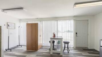 Una habitación con un armario de madera, una mesa con dos sillas y un radiador.