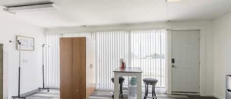 Una habitación con un armario de madera, una mesa con dos sillas y un radiador.