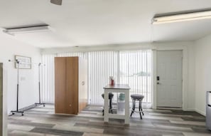 Quarto com guarda-roupa de madeira, mesa e duas cadeiras, além de radiador.