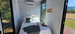 Un dormitorio moderno con cama, almohadas y ventana.