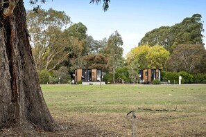 A modern building with a flat roof, surrounded by a grassy field and trees.