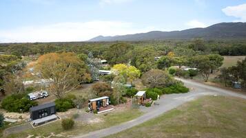 A rural property with multiple buildings, a dirt road, and surrounding vegetation.
