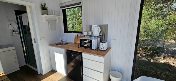 Una cocina compacta con pileta, microondas, tostadora y cafetera.