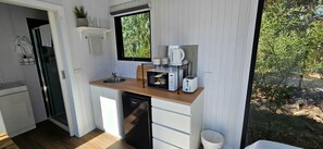 Una cocina compacta con pileta, microondas, tostadora y cafetera.
