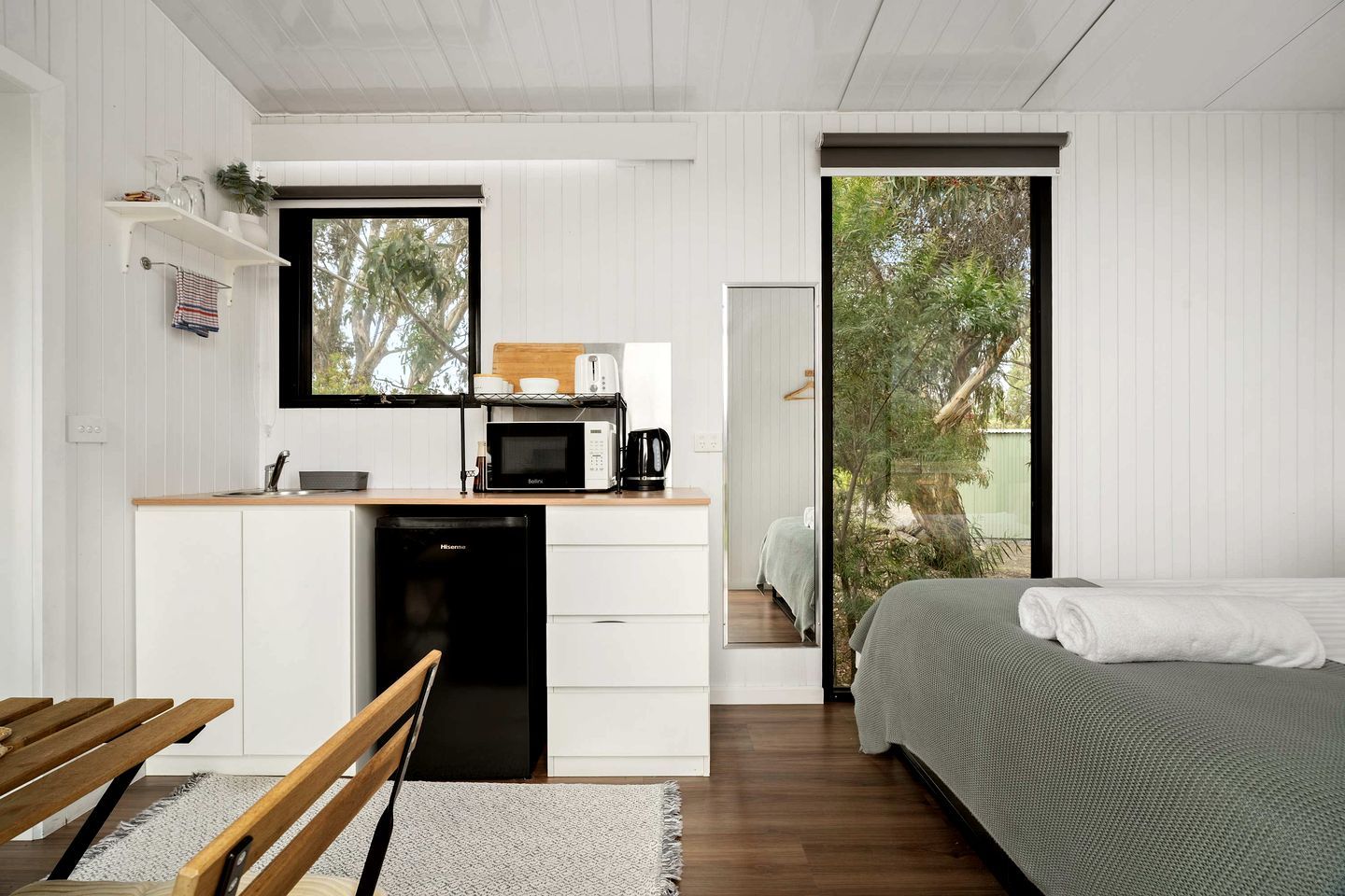 Habitación compacta con cama, escritorio y microondas, y vista al exterior.