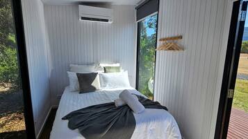 Un dormitorio moderno con cama, almohadas y ventana.