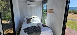 A modern bedroom with a bed, pillows, and a window.