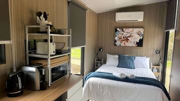 A modern bedroom with a bed, bedside tables, a desk, and a built-in wardrobe.