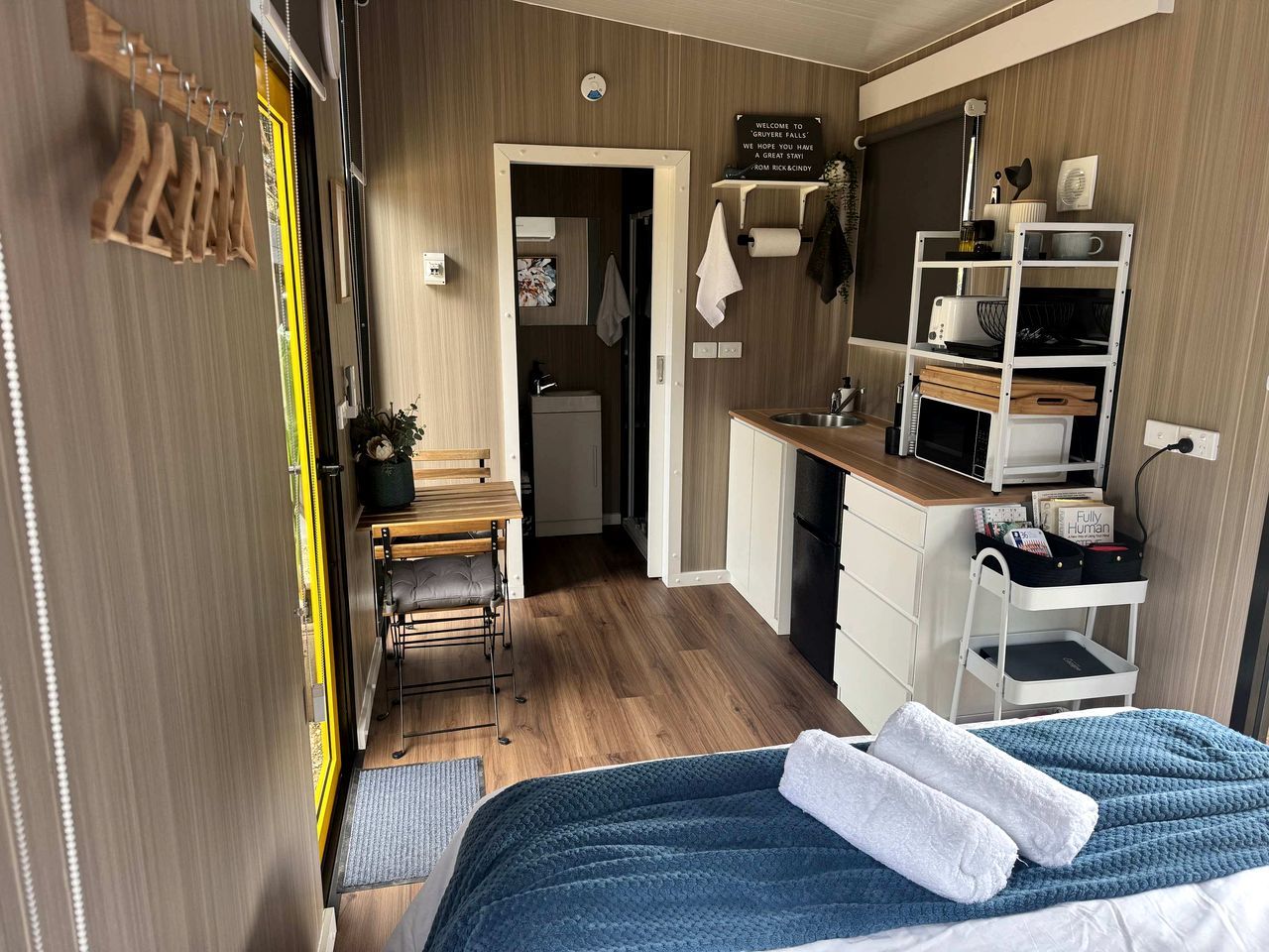 A compact room with a bed, a desk, and a kitchenette.
