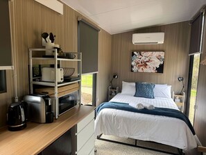 Een moderne slaapkamer met een bed, nachtkastjes, een bureau en een inbouwkleerkast.