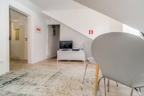 Un intérieur moderne avec un bureau blanc, un téléviseur et une chaise. Des panneaux indiquant les sorties de secours sont accrochés aux murs.