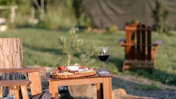 Una mesa de madera con una copa de vino tinto y un plato de comida.