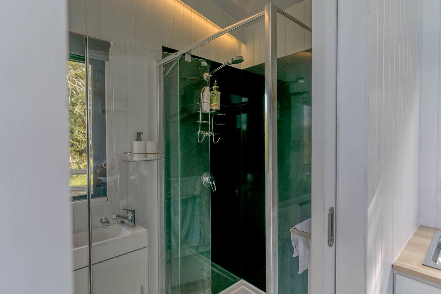 Un baño moderno con ducha acristalada, lavabo blanco y espejo.