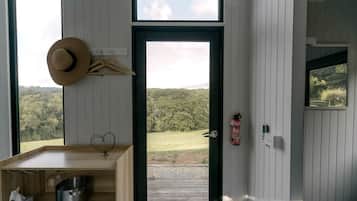 Una habitación con una mesa de madera, un sombrero en la pared, un extintor y vistas a un bosque.