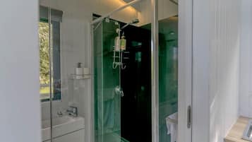 Een moderne badkamer met een douchecabine van glas, een wit wastafelmeubel en een spiegel.