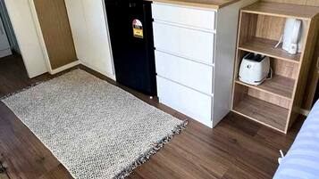 Een compacte kitchenette met een magnetron, een kleine koelkast en een broodrooster op een houten aanrecht.