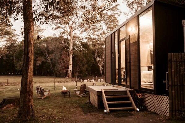 A modern cabin with a deck, a fire pit, and a view of the surrounding forest. - Sunshine Coast Glamping in a Tiny House for a Nature Escape in Queensland (Palmwoods)