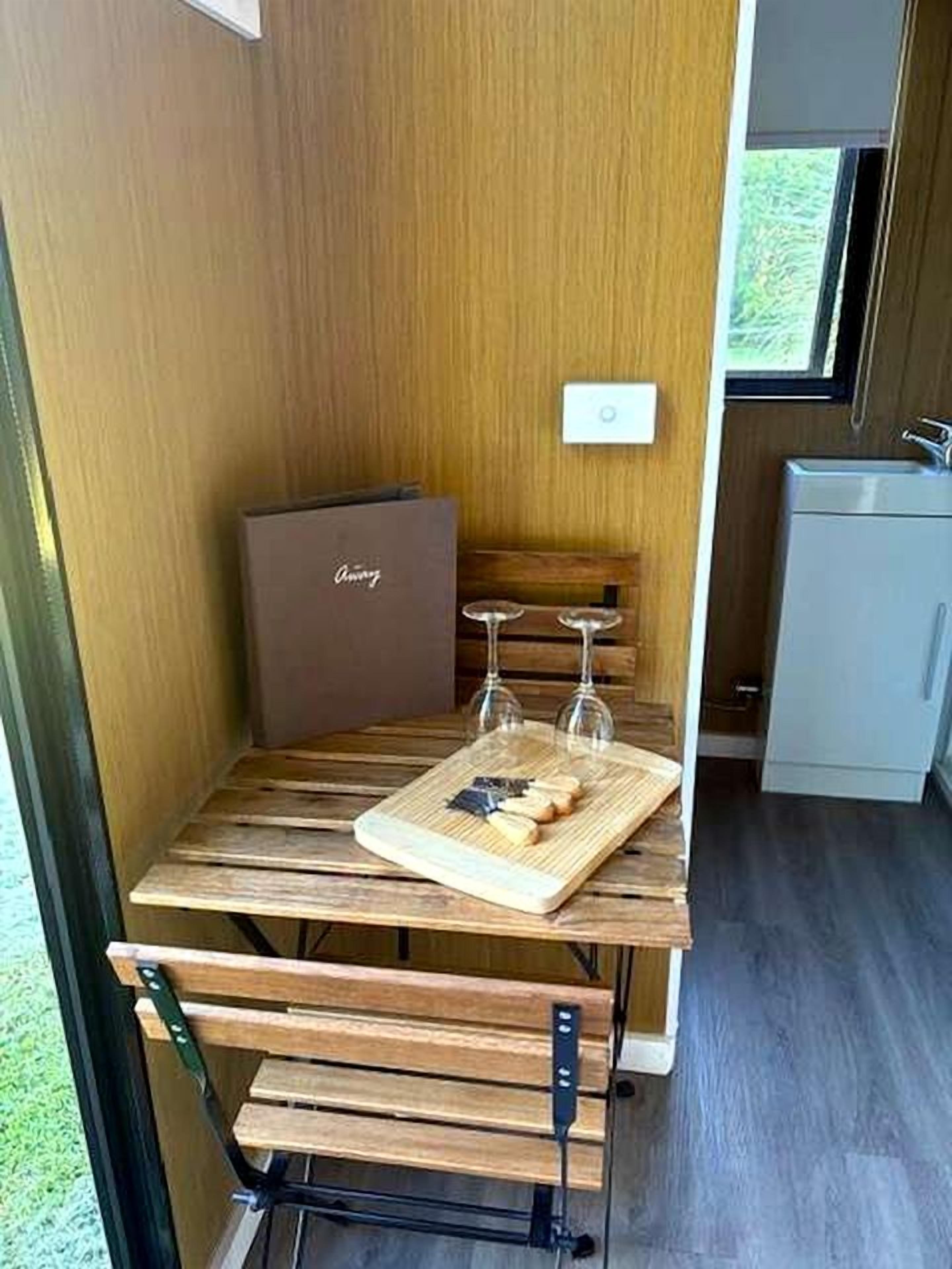 Een kleine keuken met een houten tafel, een wijnglas en een snijplank.